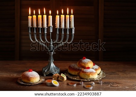 Jewish holiday Hanukkah with menorah (traditional Candelabra), donuts and wooden dreidels (spinning top), chocolate coins.  Inscription on the menorah "Olive oil"