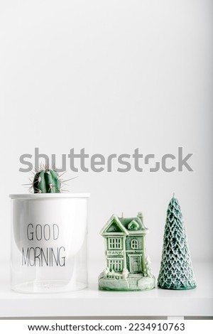 Merry Christmas decoration concept with candles and festive decor, cactus, christmas trees on light white background. Cozy home. Space for text.