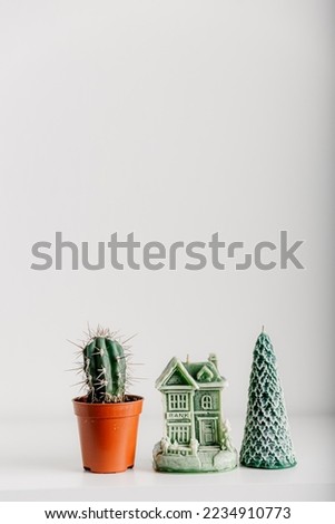 Merry Christmas decoration concept with candles and festive decor, cactus, christmas trees on light white background. Cozy home. Space for text.