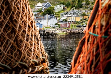 Petty Harbour Newfoundland Canada, September 19 2022: Photograph
through Lobster traps and Crab traps stacked on a boat dock at a small Atlantic town.