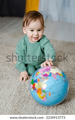 Baby boy with the geographical globe. Child exploring the world