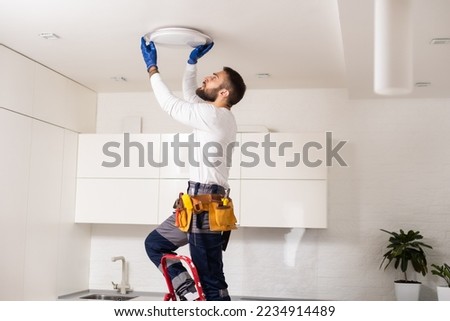 Electrician worker installation electric lamps light inside apartment. Construction decoration concept. Royalty-Free Stock Photo #2234914489