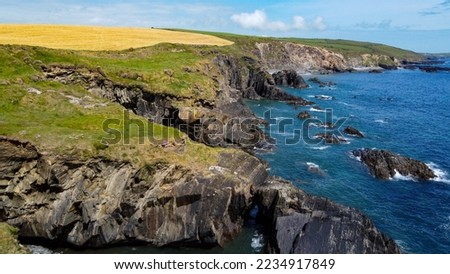 Farm fields on the rocky shore of the Celtic Sea, south of Ireland, County Cork. Beautiful coastal area. Turquoise waters of the Atlantic. Picturesque stone hills. Drone photo.