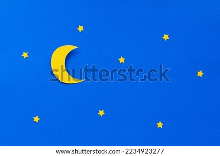 Handmade paper art Moon and stars in the blue sky. Holiday inspiration. Paper cutout on blue background. With colorful confetti for your holiday inspiration. 