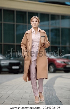 Portrait of a happy woman in business clothes after a successful business meeting with a folder with signed documents and coffee is resting near the business center. Management concept. Business rest.