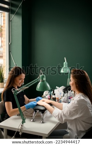 Handsome young woman manicurist doing manicure for female client. Manicure service. In professional beauty salon Royalty-Free Stock Photo #2234944417