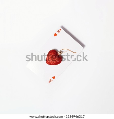 Ace of hearts, playing card with Christmas ornament, creative layout against white background. 