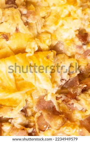 Texture of tasty scrambled eggs with bacon as background, closeup. Macro photo.