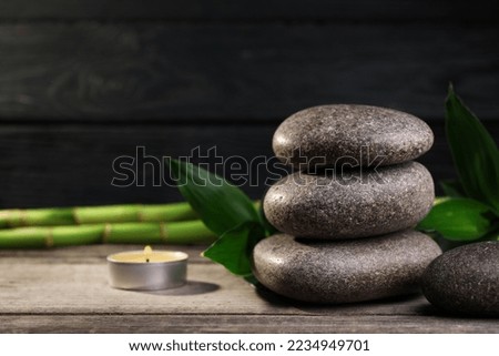 Spa stones, bamboo and candle on wooden table. Space for text