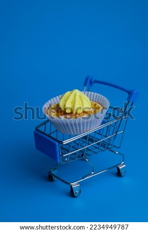 in a shopping cart is an orange in a cupcake pan garnished with a yellow mini meringue cake. for menu signage labels for cookbook splash screens
