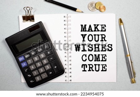 White notebook with inscription MAKE YOUR WISHES COME TRUE written in black pencil on a bright yellow background.