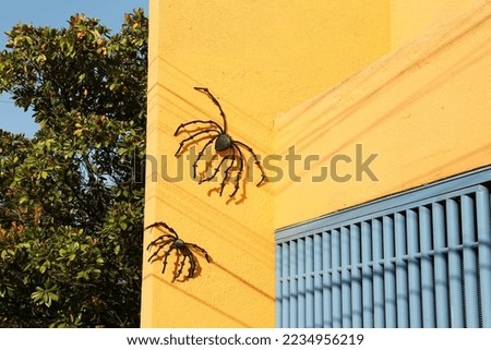 Big creepy spiders on yellow building wall. Halloween decor
