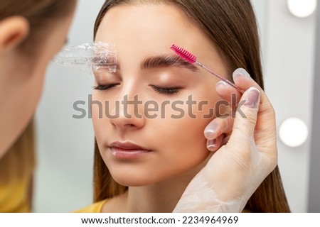 The make-up artist does Long-lasting styling of the eyebrows of the eyebrows and will color the eyebrows. Eyebrow lamination. Professional make-up and face care. Royalty-Free Stock Photo #2234964969