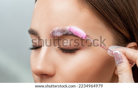 The make-up artist does Long-lasting styling of the eyebrows of the eyebrows and will color the eyebrows. Eyebrow lamination. Professional make-up and face care. Royalty-Free Stock Photo #2234964979