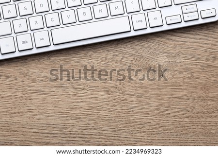 white computer keyboard on wooden background. View from above.

