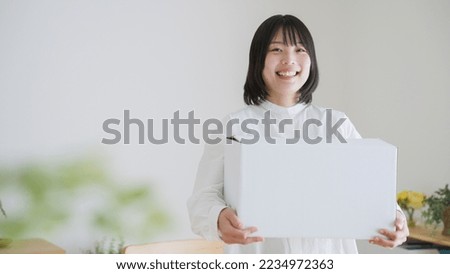 Woman holding a cardboard box with a smile Royalty-Free Stock Photo #2234972363