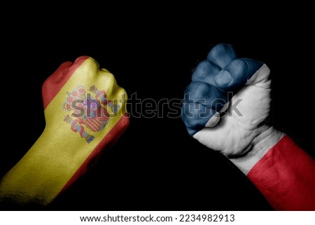 SPAIN VS FRANCE. Strong men hands painted country flags in fighting signal black background. Countries with social, economic, political, cultural, territorial, sports, financial conflicts.