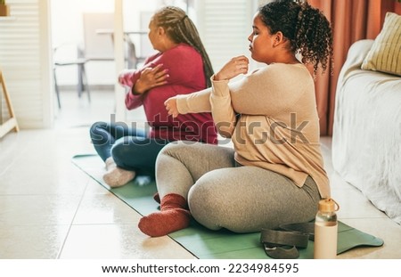 Mother and daughter doing fitness exercises at home together - Family and sport concept during winter time - Focus on girl hand