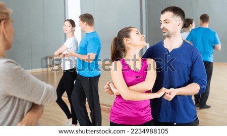 Young smiling woman and man practicing social dance moves in pair during group class