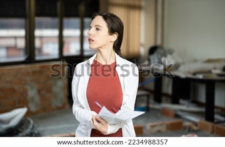 Architect woman checks according to the plan the completed repair work Royalty-Free Stock Photo #2234988357