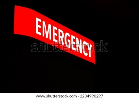 Red emergency department entrance sign at night.