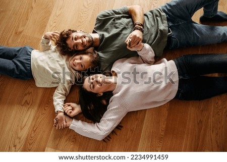 Happy family with a little girl lying on the floor Royalty-Free Stock Photo #2234991459