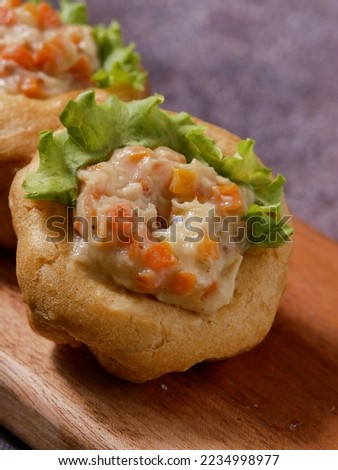 Choux pastry filled with chicken chop and vegetable garnished with lettuce, served on wooden tray selective focus with isolated background
