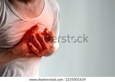 Asian young man suffering from left sided chest pain. Chest pain can be caused by heart attack, myocardial infarct or ischemia, myocarditis, pneumonia, stress, etc. Royalty-Free Stock Photo #2235001639