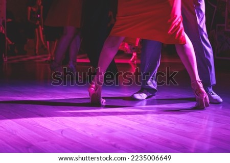 Dancing shoes of a couple, couples dancing traditional latin argentinian dance milonga in the ballroom, tango salsa bachata kizomba lesson, festival on wooden floor, purple, red and violet lights Royalty-Free Stock Photo #2235006649
