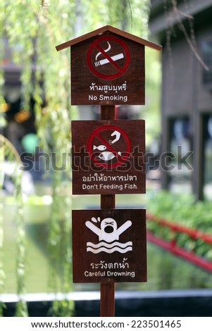 Safety wood Signs in the park,No smoking,Don't Feeding fish and Careful Drowning.