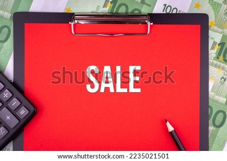 SALE - word on the background of money, a notepad and a pencil with a calculator. Business concept (copy space).