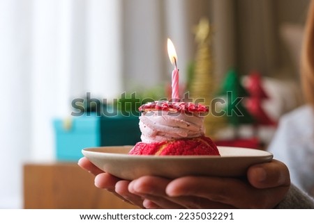Closeup image of a woman holding birthday cake with candle, Christmas holiday decoration at home