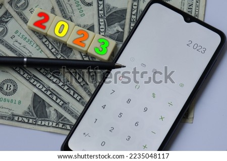 Business and finance concept. Colour number 2023 on blocks and on mobile phone screen, budget on New Year. Savings and financial events during 2023.
