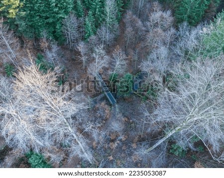 Hing angle view of small pedestrian footbridge crossing a small river in a forest in winter time.