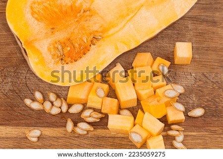 Diced slices of the butternut squash, seeds and half of the same squash cut lengthwise on the wooden cutting board, fragment top view close-up
 Royalty-Free Stock Photo #2235059275