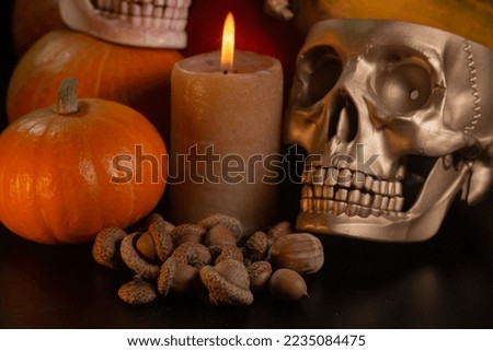 Yellow-orange pumpkins with candles and skulls on a black background the concept of Halloween and the autumn harvest of pumpkin close-up copyspace from above
