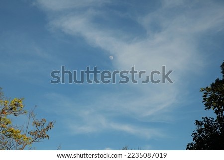 Beautiful blue sky and fluffy cloud landscape background. Moon during the day, full face of the Moon reflecting sunlight. 