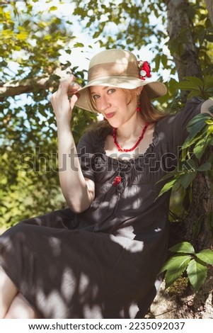 Flirtatious lady relaxing under tree scenic photography. Picture of woman in hat with natural landscape on background. High quality wallpaper. Photo concept for ads, travel blog, magazine, article
