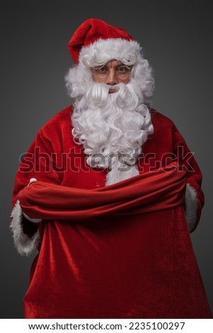 Shot of christmas santa dressed in classic red costume and glasses holding bag.
