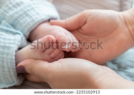 Close-up of a mother's hands cradling the feet of her newborn Caucasian child. The impact of demographic changes, birth rate and mortality Royalty-Free Stock Photo #2235102913