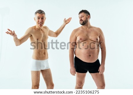 Two multiethnic men posing for a male edition body positive beauty set. Shirtless guys with different age, and body wearing boxers underwear Royalty-Free Stock Photo #2235106275
