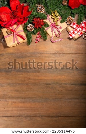 Traditional Christmas, New Year holidays background with Christmas tree branches, winter red berries, poinsettia flowers, gift boxes, on wooden background  top view copy space