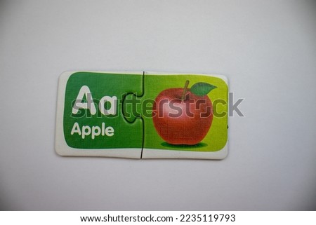 Close-up, apple picture and apple letter puzzles placed together on a white background.