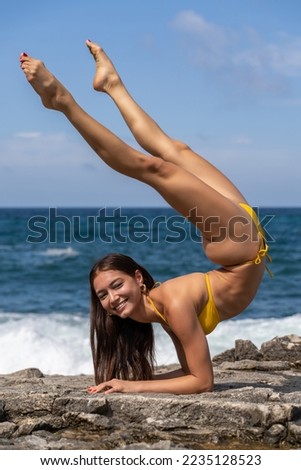 young graceful and flexible gymnast in bikini. flexibility at the beach