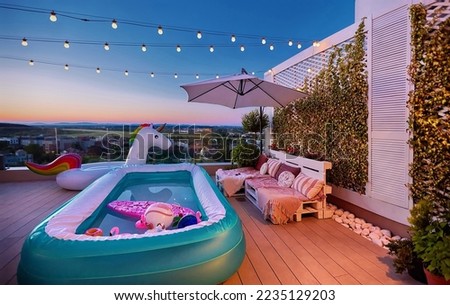 cozy rooftop patio with wooden pallet furniture, vertical garden and inflatable pool at warm summer evening Royalty-Free Stock Photo #2235129203