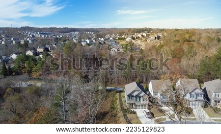 Aerial view upscale residential neighborhood situated in woodland area with fall foliage and cloud blue sky outside Atlanta, Georgia, USA. New development two story houses shingle roofs in HOA