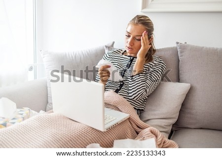 Allergic woman blowing nose in tissue sit on sofa at home office study work on laptop, ill sick girl got flu caught cold sneeze in tissue having allergy symptoms coughing holding napkin