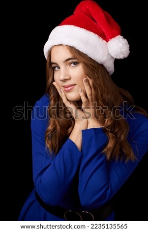 girl with long hair in blue dress wearing santa claus hat isolated on black background. High quality photo