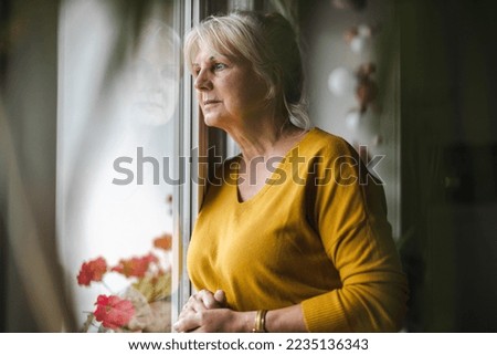 Worried elderly woman looking in window
 Royalty-Free Stock Photo #2235136343