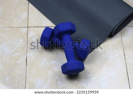 A couple of blue barbell and grey sport mattress on the floor. Indoor workout concept and healthy lifestyle. Sport equipment background.